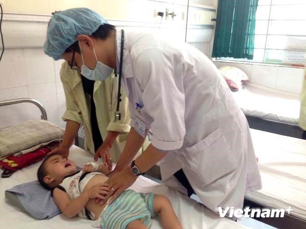 Bác sỹ của Bệnh viện Nhi Trung ương khám cho trẻ bị bệnh viêm não. (Ảnh: Thùy Giang/Vietnam+)