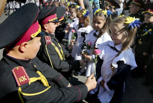 Những học sinh trong đội duyệt binh (áo sẫm) tặng hoa cho các em học sinh lớp 1 trong ngày đầu năm học mới.