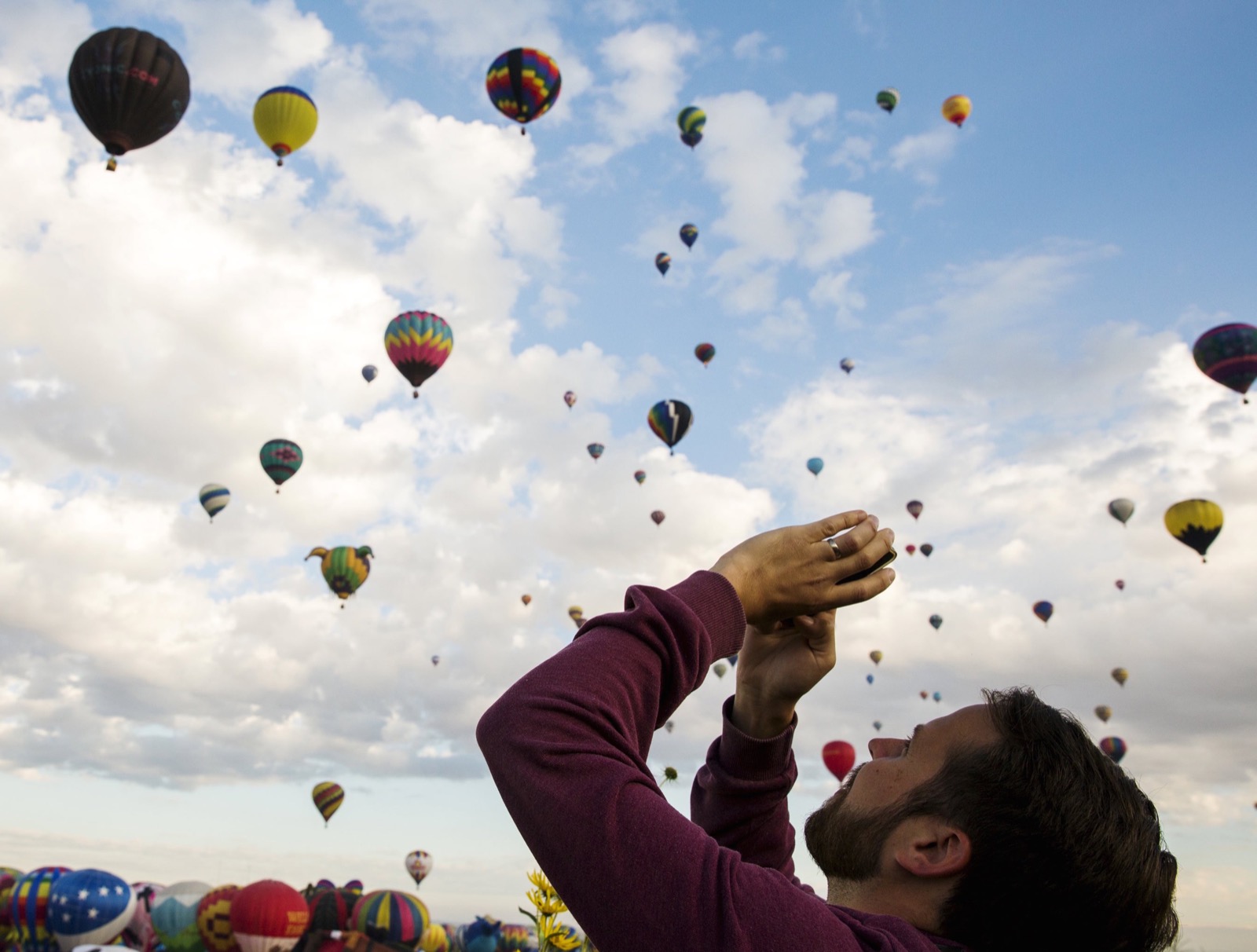 Một khách tham quan đứng dưới đất ngước cổ lên chụp những khí cầu đang bay lên cao, sau khi lễ khai mạc kết thúc. Ảnh chụp bởi Lucas Jackson.
