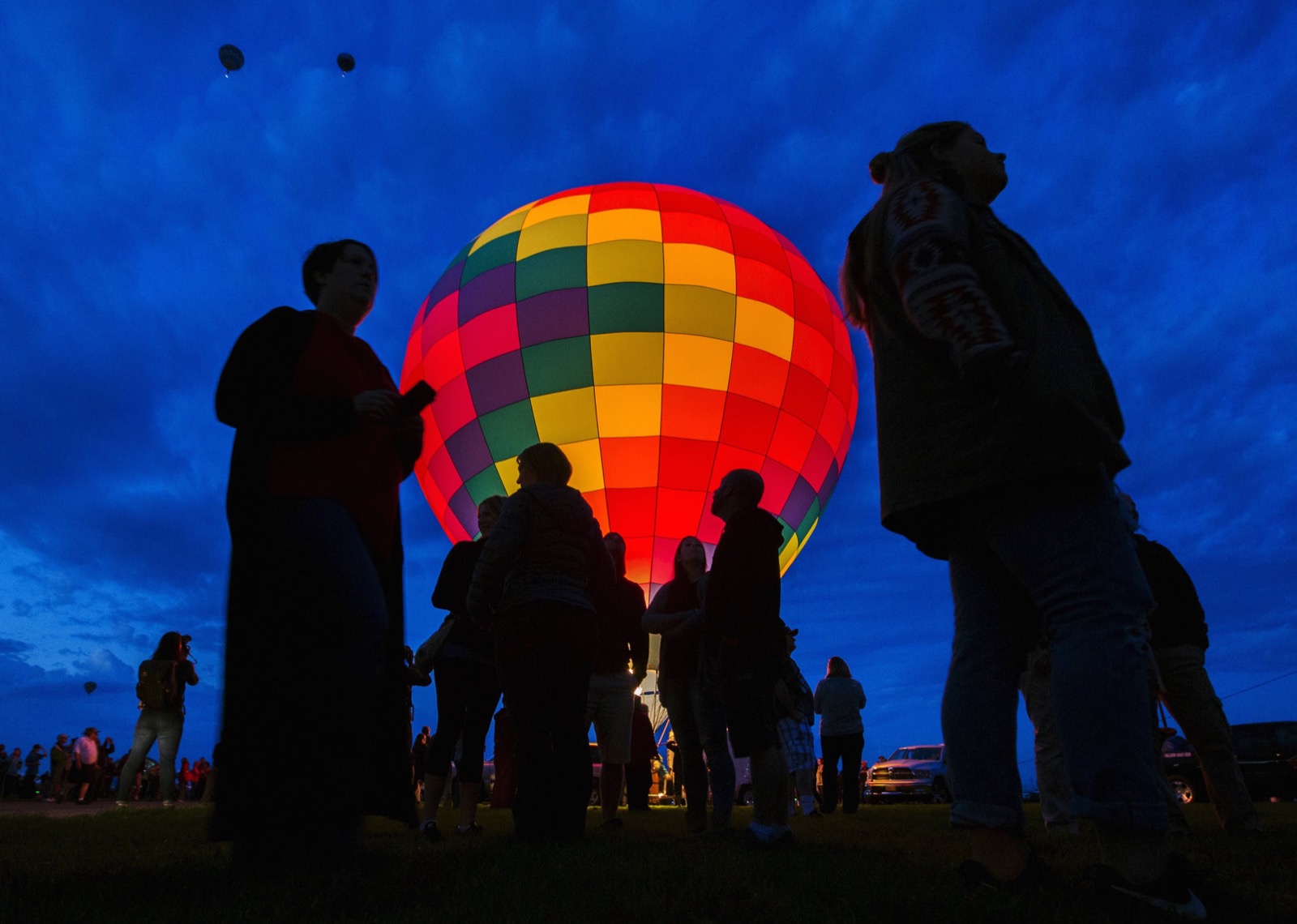 Du khách tham quan đứng cạnh một chiếc khí cầu, lúc nó đang được thử lửa trước để chuẩn bị tham gia lễ khai mạc AIBF 2015 lúc rạng sáng thứ Bảy 3/10. Ảnh chụp bởi Lucas Jackson.