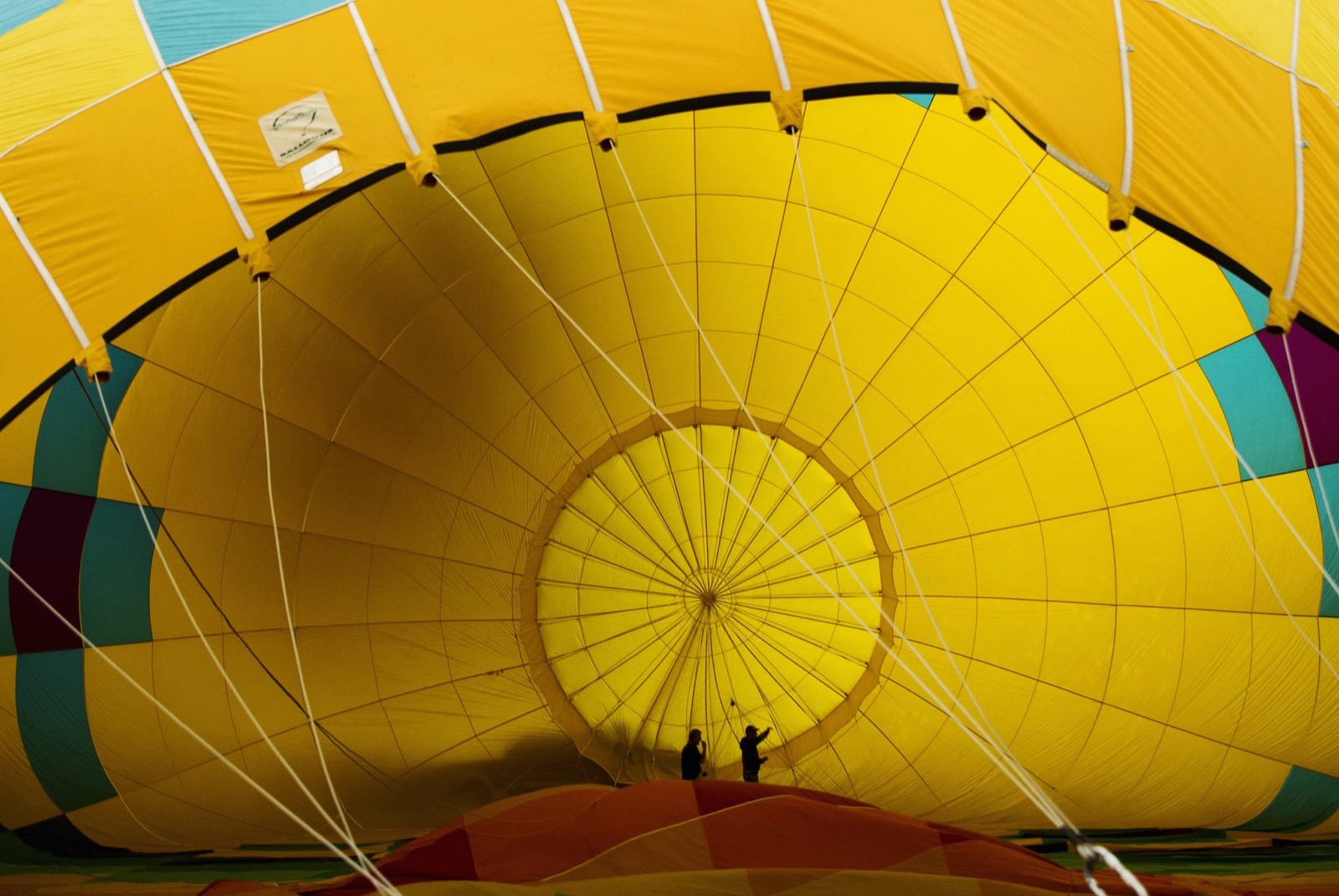 Nhìn ảnh này bạn sẽ tưởng tượng được độ khổng lồ của một chiếc khí cầu, trong hình là 2 người đàn ông đang bước vô trong lòng khí cầu để kiểm tra xem có bị rò rỉ, sứt chỉ gì hay không. Ảnh chụp bởi Lucas Jackson.