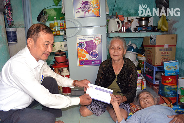 Đại diện Tổng Công ty CP Dệt may Hòa Thọ trao tiền hỗ trợ cho  bà Trần Thị Anh (người đang nằm) 
