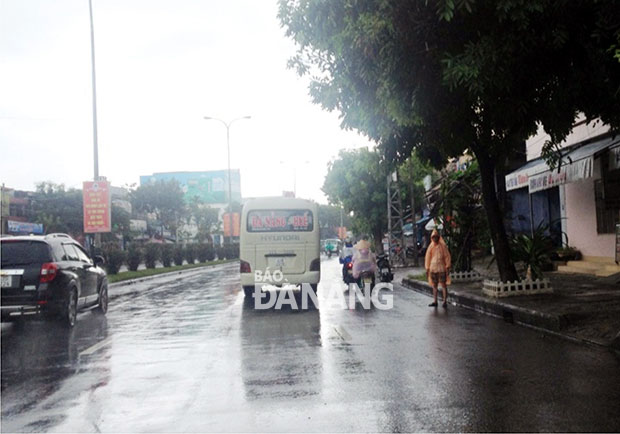 Xe dừng giữa đường, phụ xe đứng bên cạnh để cố vét khách – hình ảnh khá phổ biến trong mùa mưa này.