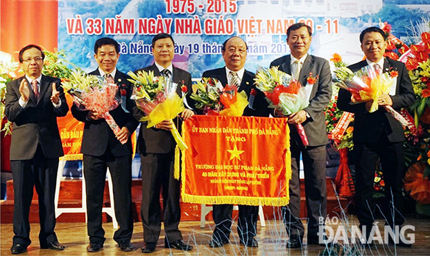 Phó Chủ tịch thường trực UBND thành phố Võ Duy Khương trao cờ truyền thống của UBND thành phố Đà Nẵng nhân kỷ niệm 40 năm thành lập Trường Đại học Sư phạm. Ảnh: BÌNH AN