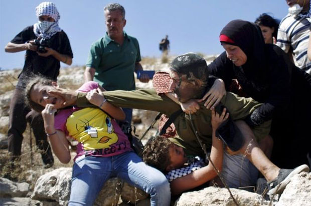 Cảnh sát Israel và người dân Palestine đụng độ ở Bờ Tây. Người dân Palestine đang cố ngăn cản một cảnh sát Israel bắt cậu bé đồng hương ở làng Nabi Saleh ở Bờ Tây khi xảy ra cuộc phản đối chống người Do Thái định cư. Ảnh: Mohamad Torokman