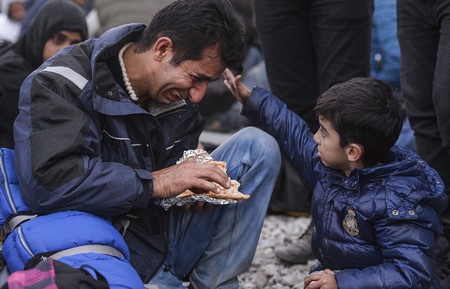 Một đứa trẻ đang chạm vào người cha đang khóc của mình trong cuộc biểu tình của người nhập cư từ Pakistan và Ma-rốc tại Macedonia. Macedonia vừa siết chắt luật nhập cư, chỉ cho phép người di cư đến từ Syria, Iraq và Afghanistan đi vào lãnh thổ của mình, bỏ rơi hàng ngàn người di cư khác.