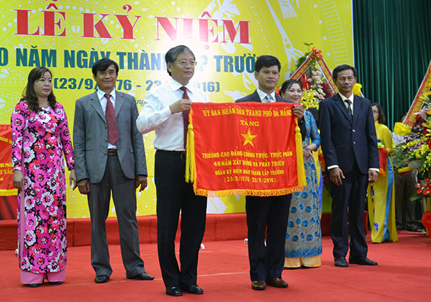 Phó Chủ tịch UBND thành phố Nguyễn Ngọc Tuấn (bên trái) tặng cờ thi đua cho Trường Cao đẳng Lương thực - Thực phẩm.