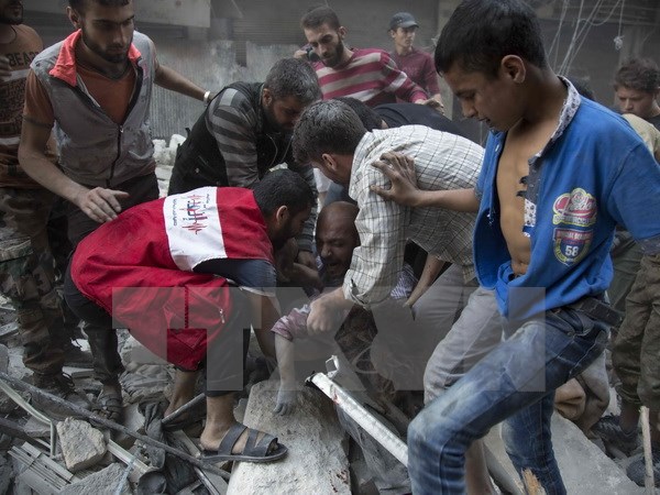Một người đàn ông đau khổ sau khi tìm thấy xác con dưới những đống đổ nát sau các vụ không kích tại Aleppo ngày 27-9. Ảnh: AFP/TTXVN