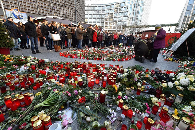 Người dân Đức đặt nến và hoa ở chợ Giáng sinh để tưởng niệm các nạn nhân thiệt mạng trong vụ tấn công ngày 19-12-2016. 		Ảnh: AP 
