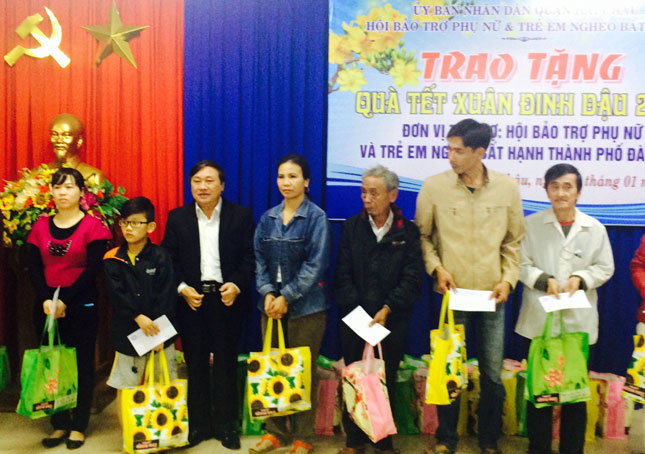 Chủ tịch Hội Bảo trợ Phụ nữ và Trẻ em nghèo bất hạnh thành phố Huỳnh Văn Hoa (thứ ba, trái sang) trao quà cho đại diện các gia đình