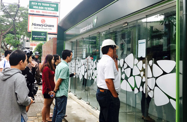 Các khách hàng chờ đợi đến lượt mình để rút tiền tại các cây ATM.