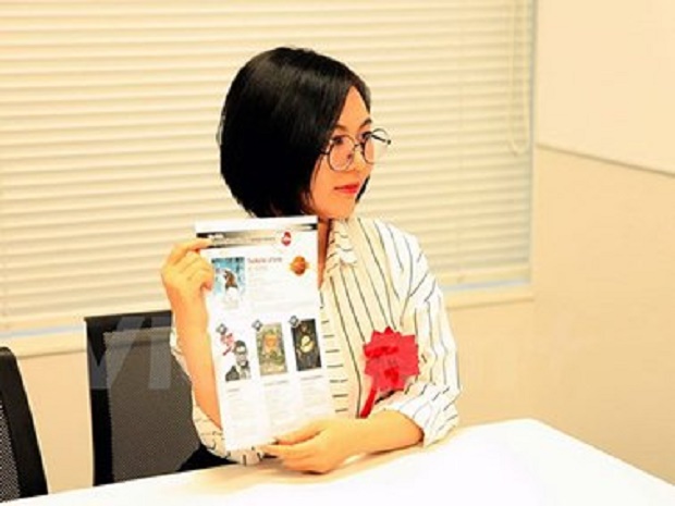 Author Can Tieu Hy poses for photos next to the banner of the 10th Japan International Manga Award in Japan - PHOTO: TTXVN