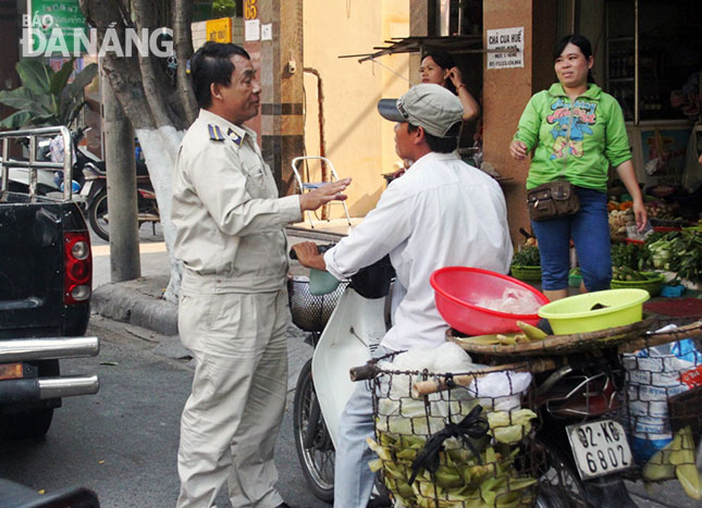 Đội Kiểm tra quy tắc đô thị quận nhắc nhở một trường hợp bán hàng rong trên đường Nguyễn Thị Minh Khai.              Ảnh: HOÀNG HIỆP