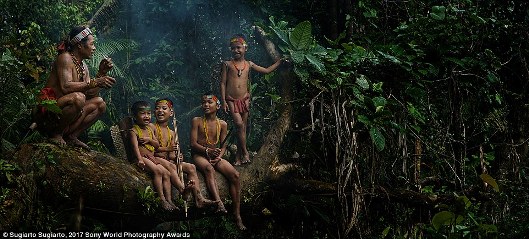 Trong rừng Sumatra Barat, Indonesia, trẻ em ngồi chơi với một người cao tuổi của bộ lạc Mentawai trên đảo Mentawai.