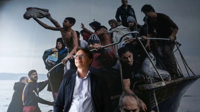 Sergey Ponomarev đứng trước bức ảnh những người tị nạn vượt biển.(In trên The New York Times - 16-11- 2015). 