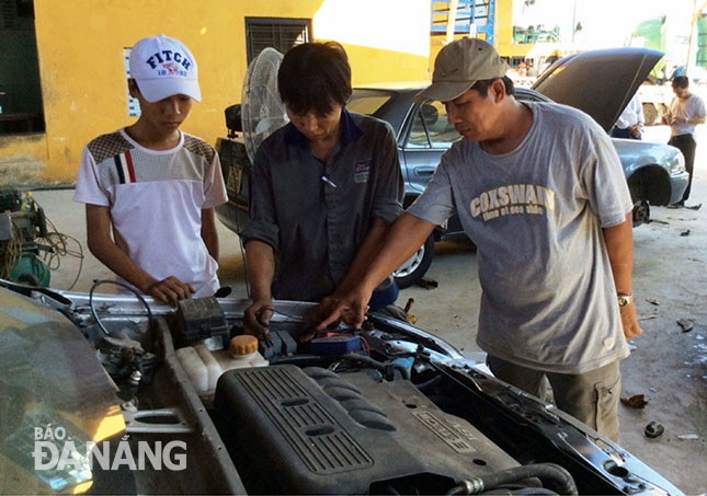 Hoạt động của kinh tế tập thể vừa tạo việc làm cho xã viên vừa đào tạo nghề cho người lao động. Trong ảnh: Ông Trần Nhật Ninh (phải), Giám đốc Hợp tác xã ô-tô Liên Chiểu hướng dẫn cho các học viên sửa chữa ô-tô.  