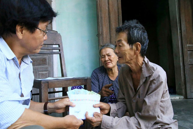 Ông Huỳnh Mật (phải) nhận món quà chia sẻ của các nhà hảo tâm gửi tặng. (Ảnh do nhân vật cung cấp)