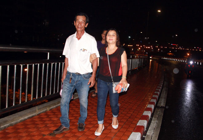 Các du khách đến từ Hà Nội đội mưa và gió ở giữa cầu Thuận Phước chờ đón vũ điệu pháo hoa trên sông Hàn
