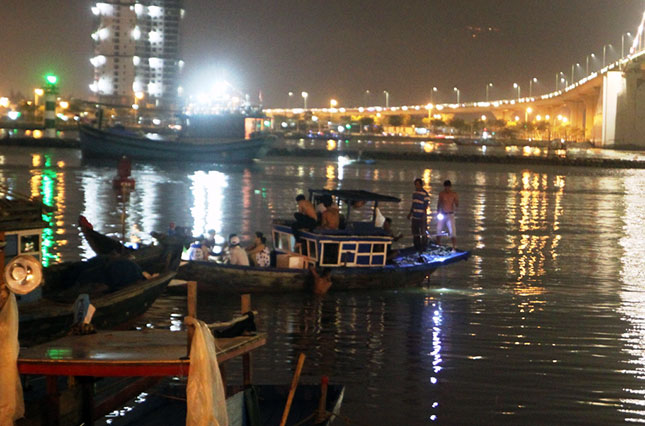 Một thuyền chở người bắt đầu tiến ra giữa sông Hàn xem pháo hoa và ngay giữa sông là một tàu cá đang tổ chức ăn uống, xem pháo hoa đông người trên nóc tàu.  	                                                                              Ảnh: HOÀNG HIỆP