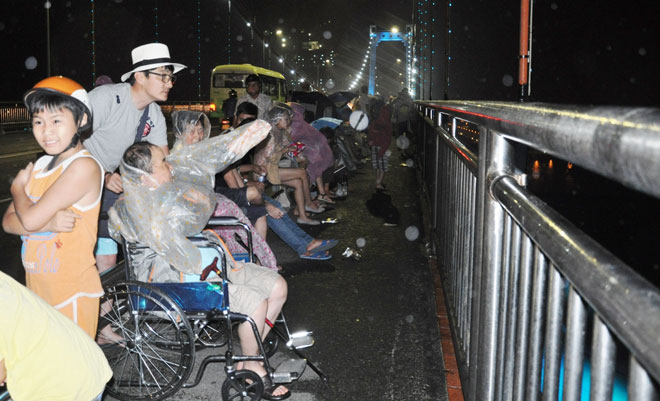 2. Trên cầu lúc này, cả những người khuyết tật cũng chọn cho mình chỗ xem ưng ý, dù mưa mỗi lúc một to- Thanh tình.