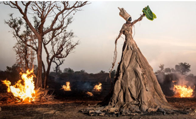 Người phụ nữ, được trang trí để tượng trưng cho một cái cây, ở trung tâm của một ngọn lửa. 