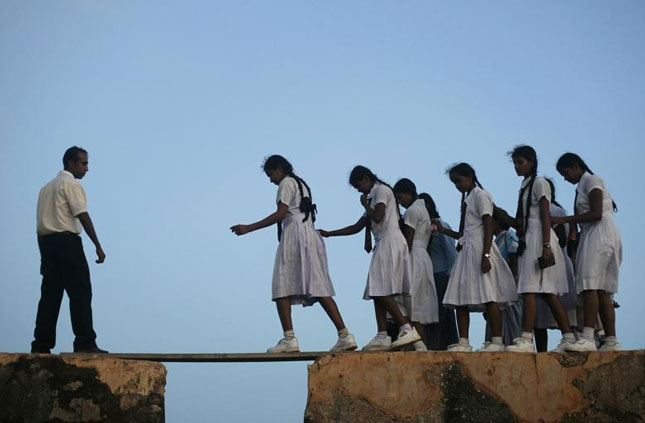 Các nữ sinh Sri Lanka bước qua tấm ván trên tường của pháo đài Galle thế kỷ 16 để tới trường.