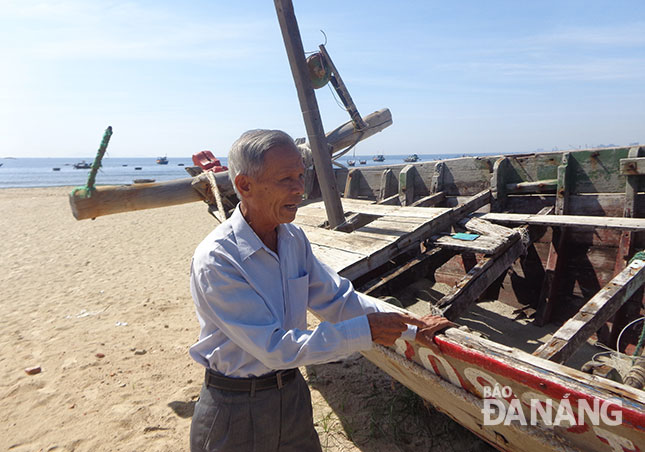 Nghỉ nghề biển từ năm 2008, ông Ngô Văn Đưa vẫn thường ra biển chạm tay vào mạn thuyền, nhớ biển. Ảnh: Q.T