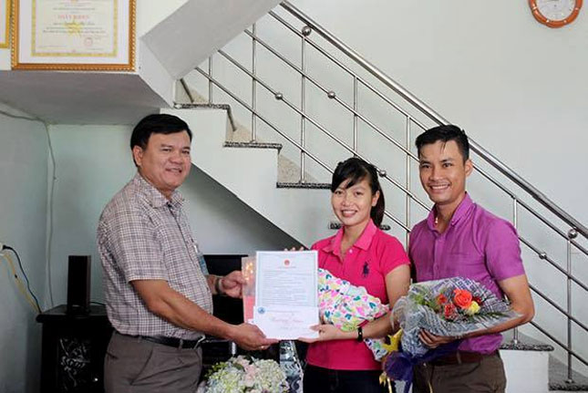 Chủ tịch UBND phường Hòa Hải Nguyễn Văn Hiền (trái) trao giấy tờ “3 trong 1”, hoa và quà cho một gia đình có thêm thành viên trên địa bàn phường.