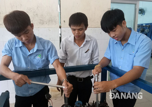 Trần Tấn Bửu (bìa phải) đang thực hành nghề công nghệ ô-tô trong giờ học tại Trường Cao đẳng nghề Đà Nẵng.