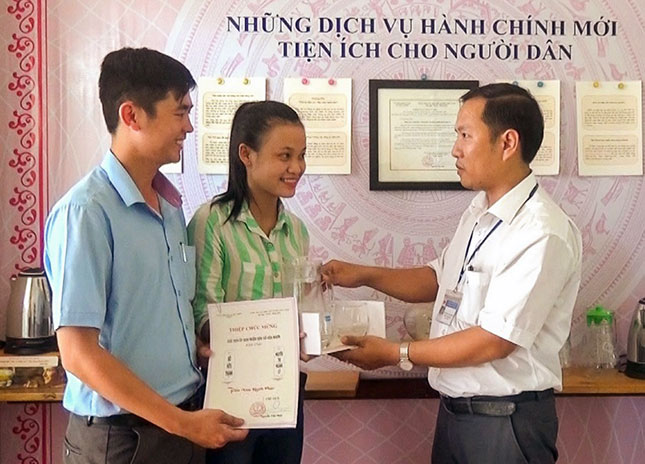 Chủ tịch UBND xã Hòa Nhơn Nguyễn Tấn Phát (bên phải), một cán bộ trẻ trưởng thành từ Đề án 89, trao giấy đăng ký kết hôn cho công dân.