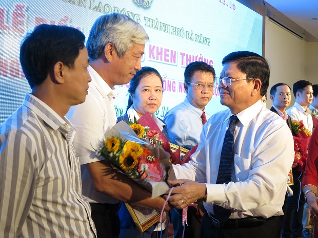 Municipal Party Committee Deputy Secretary Vo Cong Tri (right) presenting flowers to the honourees