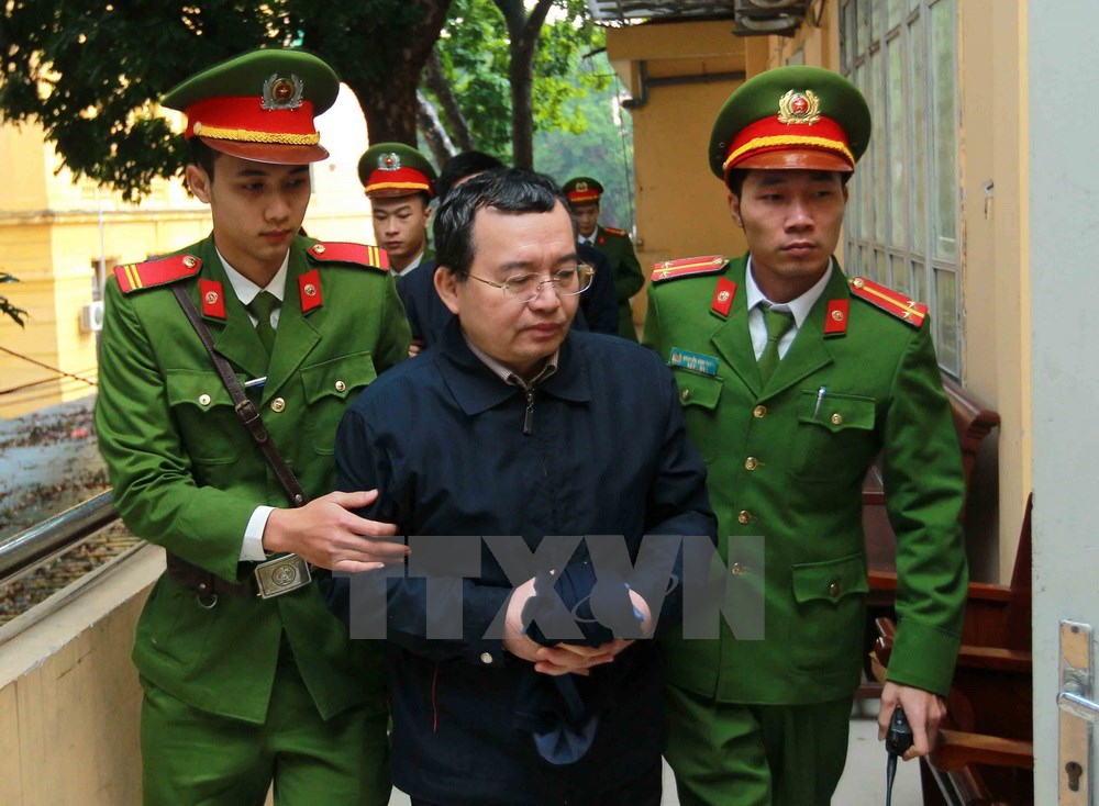 Cảnh sát dẫn giải bị cáo Nguyễn Quốc Khánh vào phòng xét xử. (Ảnh: Doãn Tấn/TTXVN)