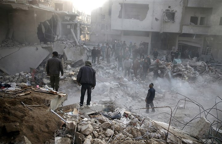Người dân tụ tập ở khu vực một tòa nhà bị san phẳng sau trận không kích ở Hamouriyeh. Ảnh: Reuters.