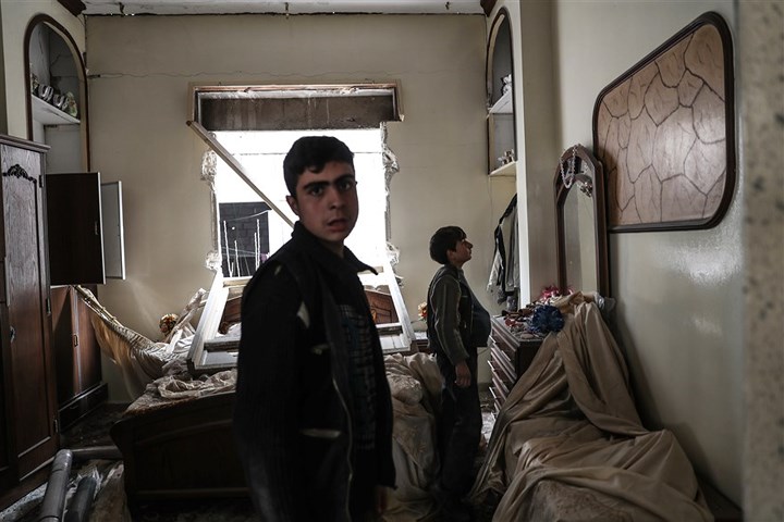 Các cậu bé bên trong một ngôi nhà bị tàn phá nặng nề sau các đợt không kích ở Mesraba. Ảnh: EPA.