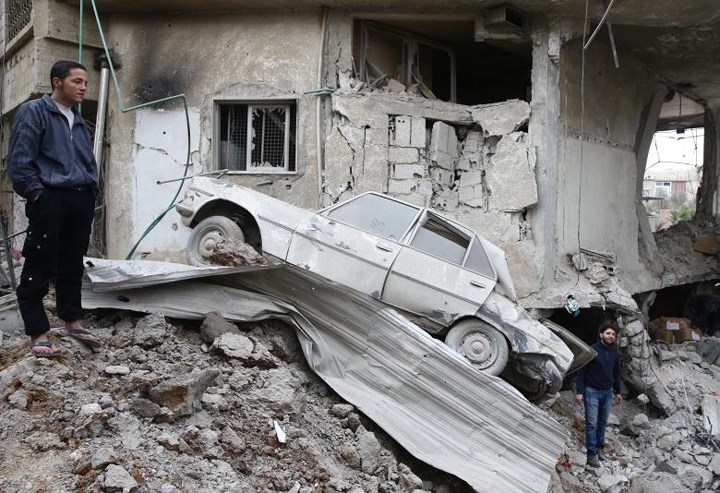 Chiếc ô tô nằm chỏng chơ bên đống đổ nát của một tòa nhà. Ảnh: Reuters.