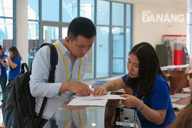 Các tình nguyện viên tại Trung tâm Báo chí quốc tế APEC (áo sẫm) hỗ trợ thông tin cho các phóng viên đến đăng ký tác nghiệp.