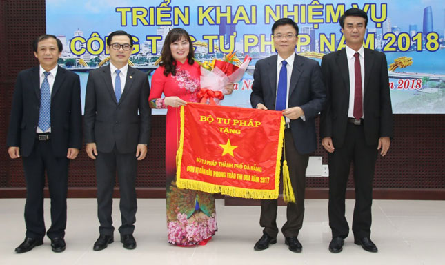 Bộ trưởng Bộ Tư pháp Lê Thành Long (thứ hai, phải sang) trao Cờ đơn vị dẫn đầu phong trào thi đua năm 2017 cho Sở tư pháp thành phố. Ảnh: TRÂM ANH