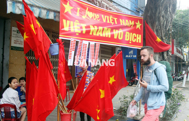 Một người nước ngoài hỏi mua áo thun đỏ để cổ động cho đội U23 Việt Nam. Ảnh: HOÀNG HIỆP