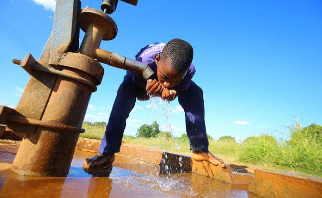 Một cậu bé Zimbabwe uống nước từ giếng đóng ở Chegutu, cách thủ đô Harae  (Zimbabwe) 100km về phía tây.