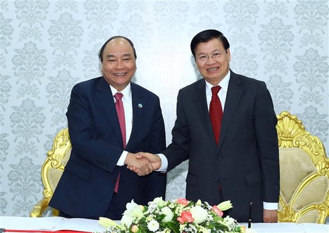 Prime Minister Nguyen Xuan Phuc (L) shakes hands with his Lao counterpart Thongloun Sisoulith at the inaugural ceremony of the Star Telecom's new headquarters (Photo: VNA)