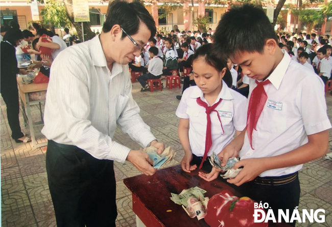 Giáo viên và học sinh Trường THCS Lê Độ (quận Sơn Trà) chung tay thực hiện chương trình “Nuôi heo đất giúp bạn đến trường”.
