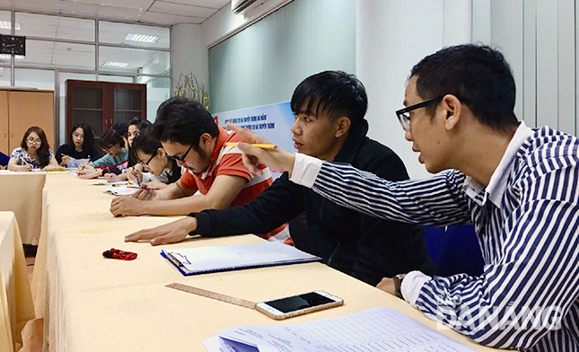 Thầy Đặng Quang Vinh (bìa phải) hướng dẫn học viên trong lớp học thiết kế đồ họa.