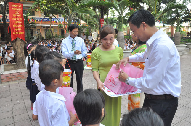 Trước khi được bầu giữ chức Phó Chủ tịch UBND quận Liên Chiểu, ThS. Lê Văn Nghĩa (bìa phải) đã có 20 năm công tác trong ngành giáo dục. Trong ảnh: ThS. Lê Văn Nghĩa trao quà cho học sinh tại một trường học trên địa bàn quận Liên Chiểu. 	                           Ảnh: TÚ PHƯƠNG