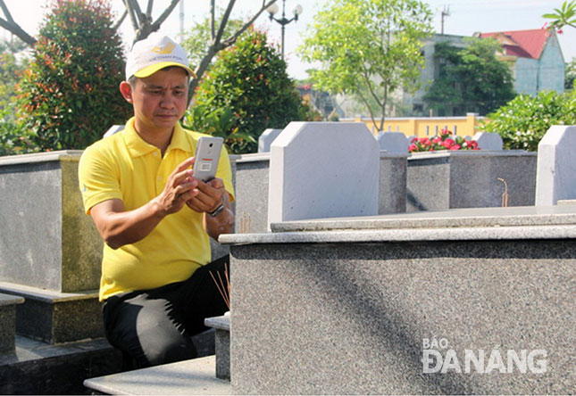 Nhân viên Bưu điện thành phố đang tiến hành chụp hình bia mộ liệt sĩ tại Nghĩa trang Liệt sĩ xã Hòa Tiến, huyện Hòa Vang.