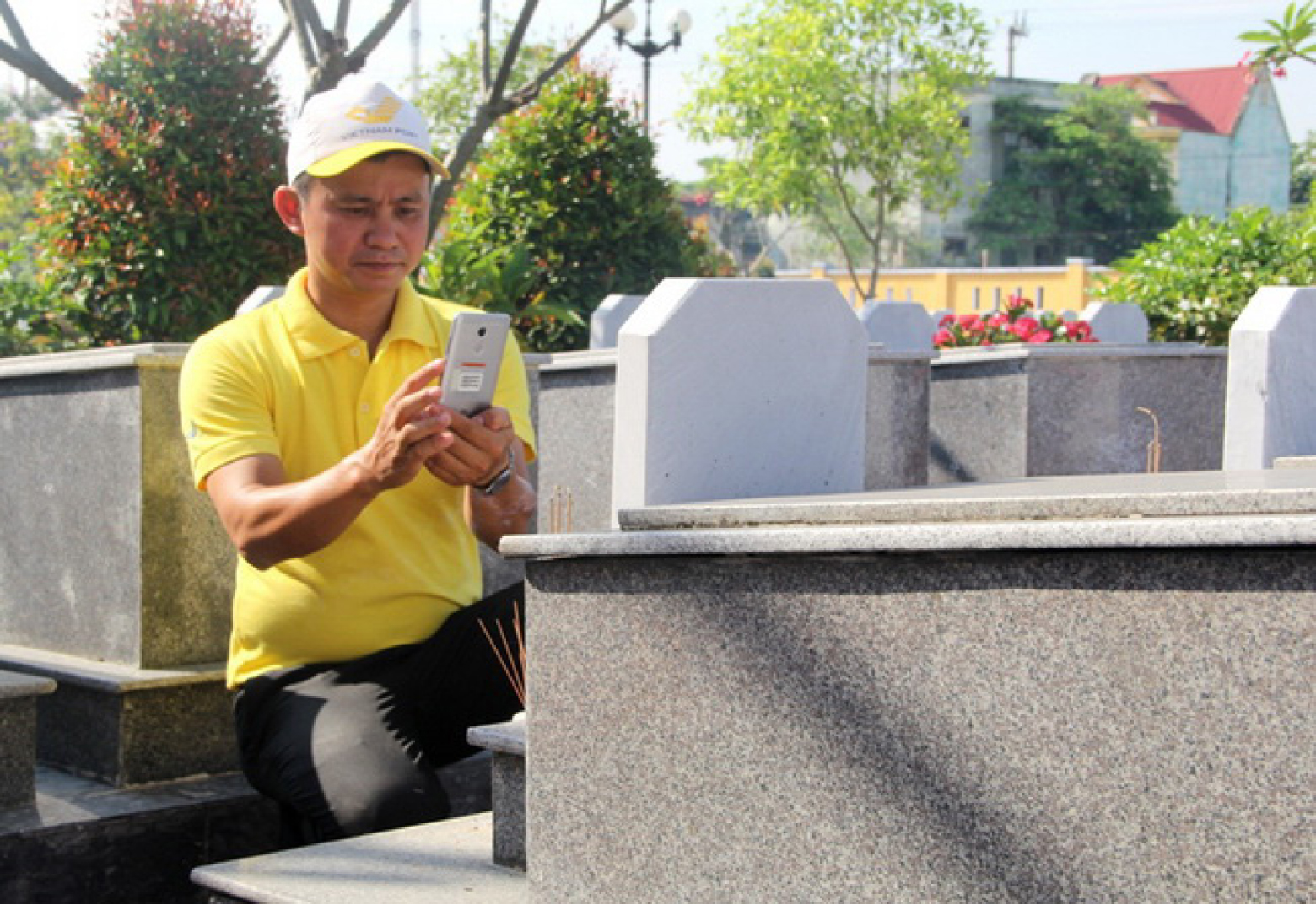 A post office employee tooking photos of graves the Hoa Tien Commune Martyrs’ Cemetery