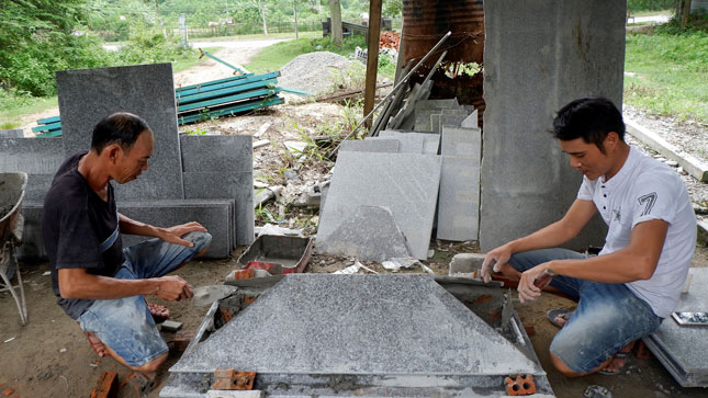 Anh Vũ Quân (bên phải) (Cơ sở đá granite Huy Cường) lắp ráp phần nắp mộ. Ảnh: Mai Hiền