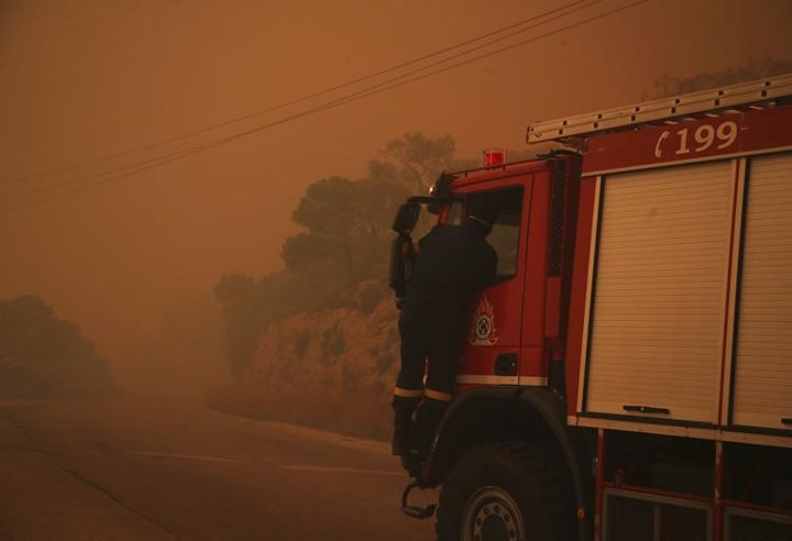   Một chiếc xe tải chìm trong màn khói mịt mùng trên con đường gần Kineta, phía tây Anthens. Ảnh: AP