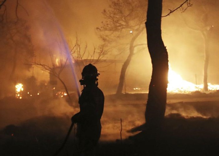 Một người lính cửu hỏa đang phun nước chữa cháy. Chính quyền địa phương đã ban bố tình trạng khẩn cấp ở các vùng phía đông và phía tây Athens do đám cháy đã lan ra khắp rừng thông và các khu dân cư ven biển. Ảnh: AP 