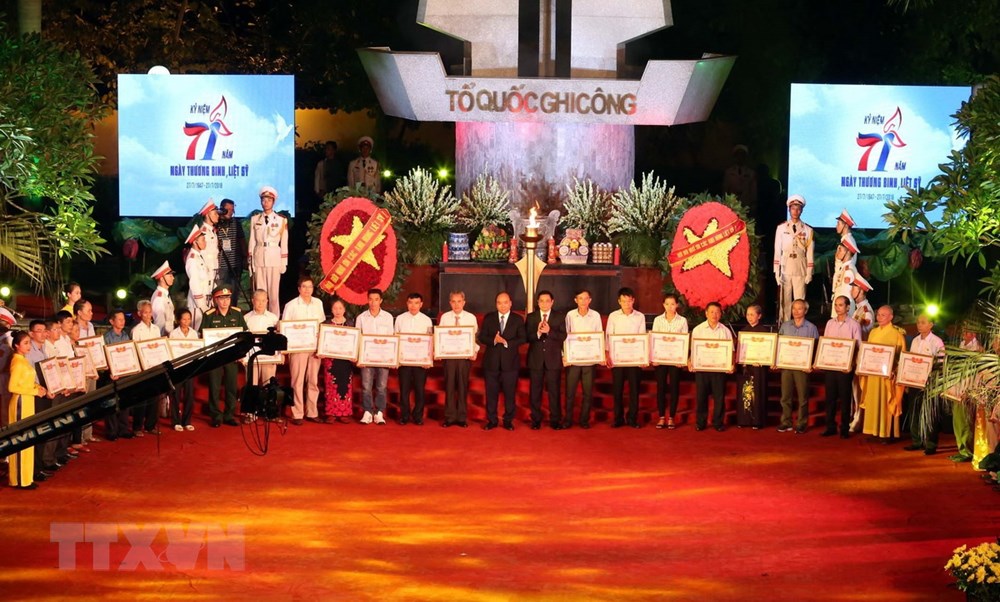 Thủ tướng Nguyễn Xuân Phúc trao Bằng Tổ quốc ghi công cho 30 thân nhân liệt sỹ đại diện cho trên 400 gia đình liệt sỹ tại buổi lễ tối 26/7. (Ảnh: Anh Tuấn/TTXVN)