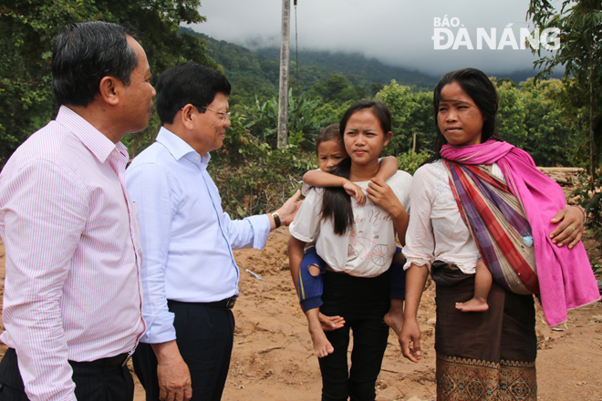 Phó Bí thư Thường trực Thành ủy Võ Công Trí (thứ hai, bên trái) thăm hỏi tình hình của người dân tỉnh Attapeu sau sự cố vỡ đập thuỷ điện
